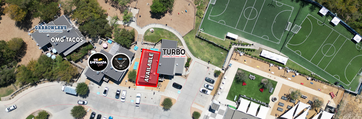 Aerial view of a mixed-use entertainment and dining area with an available commercial space highlighted in red beside Turbo Coffee & Creative, near OMG Tacos, The Empanada Cookhouse, outdoor gathering areas, and adjacent soccer fields.